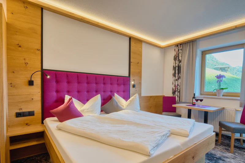 Schlafzimmer mit Doppelbett und Fenster ins Grüne