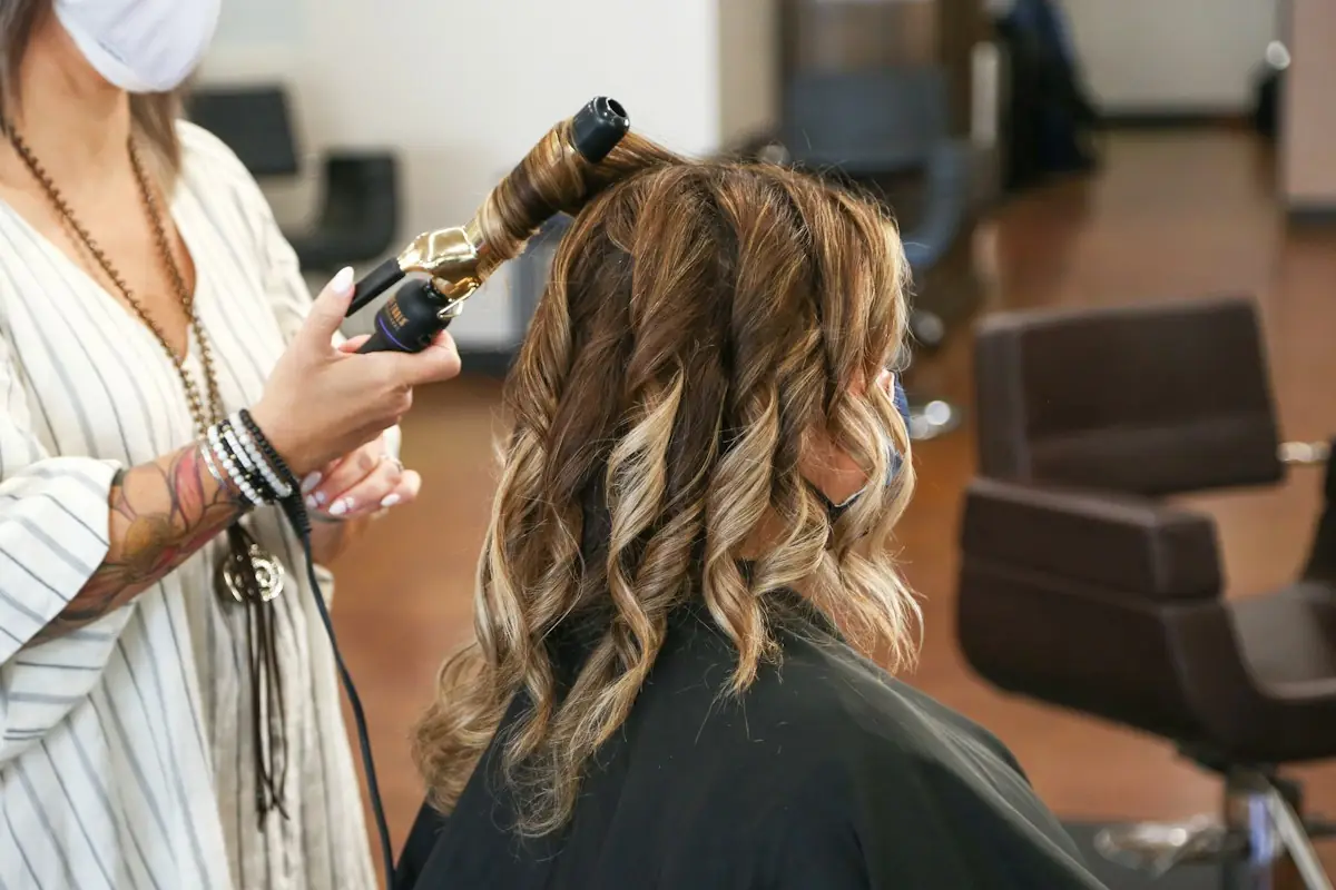 Coiffeuse lockt einer Kundin die Haare mit dem Lockenstab