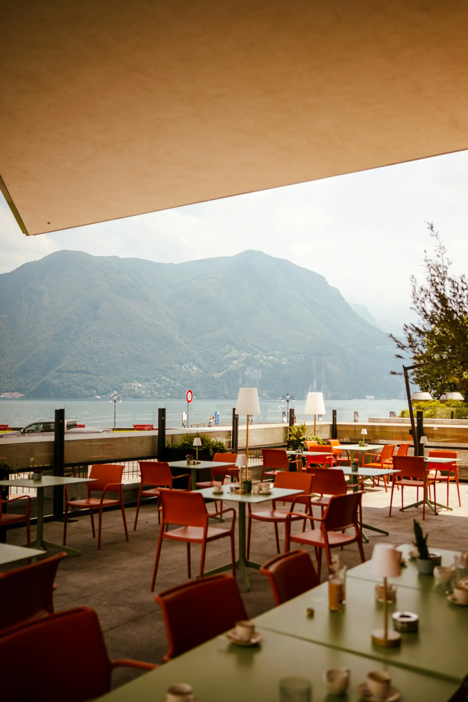 Restaurantterrasse mit roten Stühlen und Blick auf See und Berge
