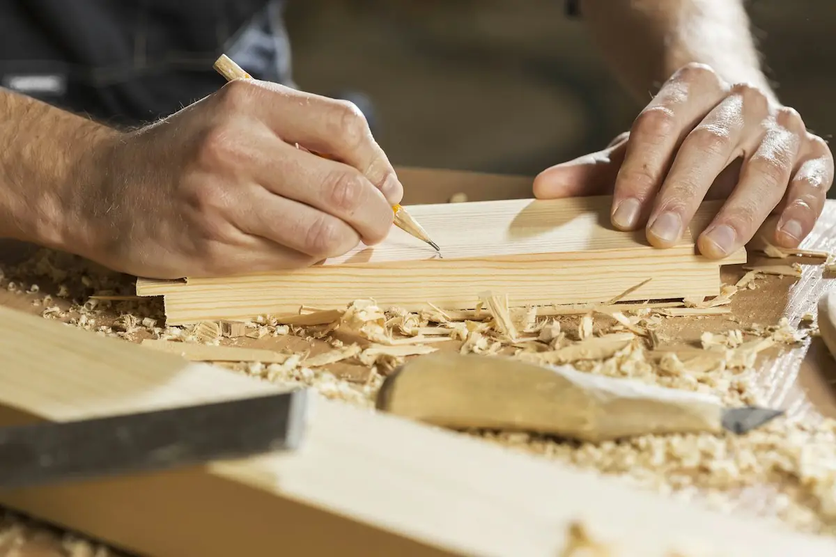 Schreiner zeichnet mit Bleistift eine Linie auf ein Holzstück