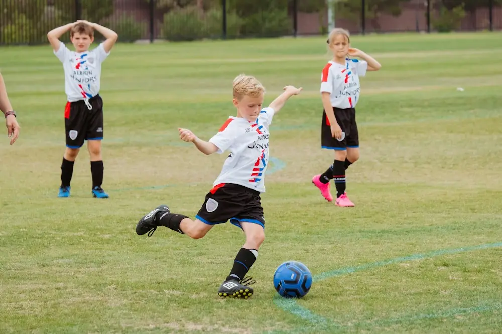 Kind schiesst im Training auf das Tor, andere Kinder schauen zu